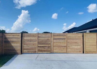 Modern horizontal wood fence with a driveway gate
