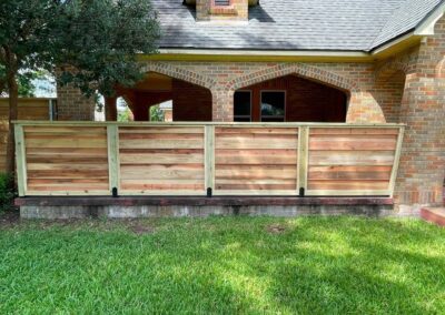 Horizontal cedar fence in front of a brick porch